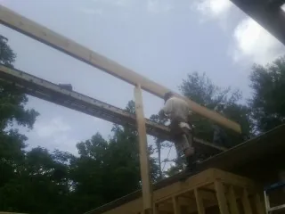Carpenter setting a ridge beam over a new addition frame — Ice Dam Removal by Roofing Brothers in Sixes