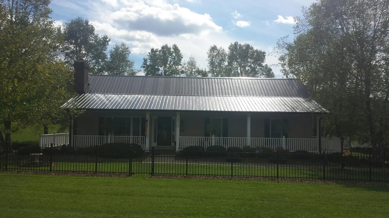 Gray metal roof on a brick ranch with a full width front porch — Gutter Guard Installation work by our crew in Sixes
